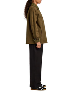 Person wearing a green jacket and black pants on a white background