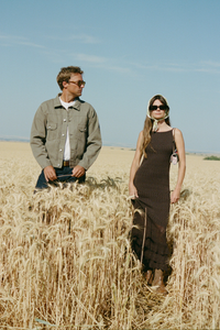 Two people standing in a wheat field with clear blue sky