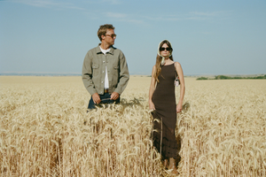 Two people standing in a wheat field with a clear sky.