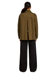Person wearing a green jacket and black pants on a white background