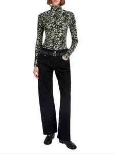 Person wearing a patterned long-sleeve top and black pants on a white background
